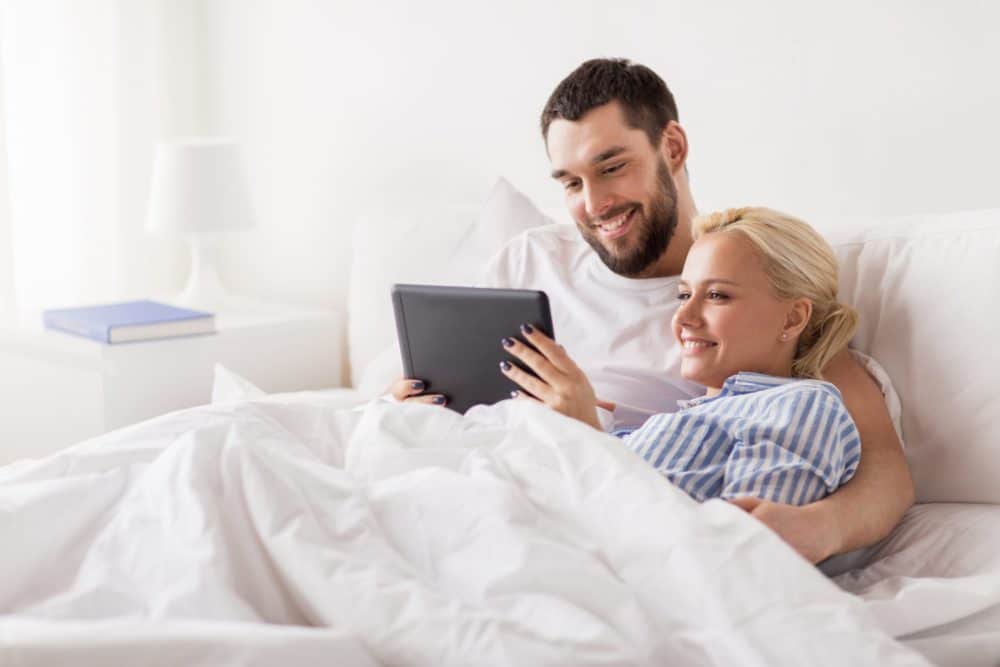 smiling happy couple with tablet pc in bed at home Sfeerfoto - Dexitex